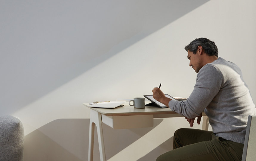 A person uses a Surface device at a table.