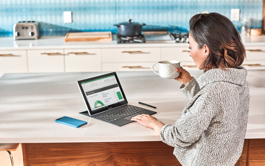 A person drinks coffee while using a Surface device.