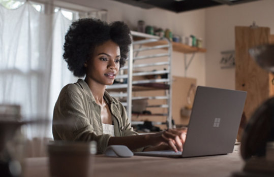 A woman uses her Surface Laptop at a desk.