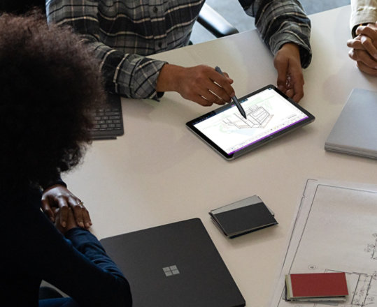 Des collègues travaillant ensemble sur un Surface Go 2 avec OneNote, un Surface Book 3 et un Surface Pro X.