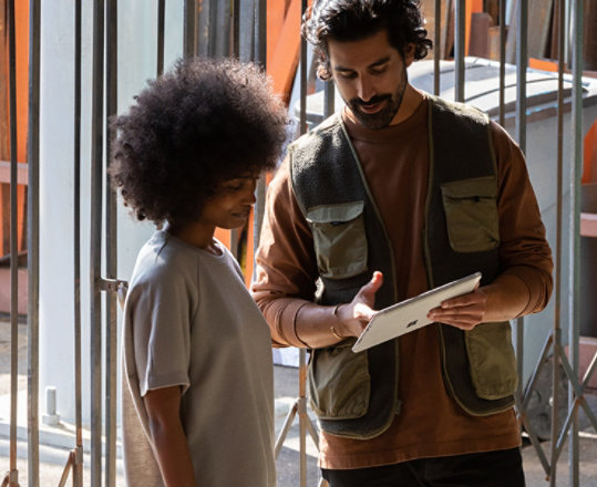 Un uomo presenta qualcosa a una donna sul suo Surface Pro 7 for Business in modalità tablet.
