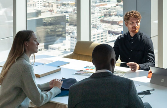 Two men and a woman having a meeting in a high rise