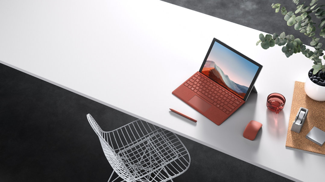  Een Surface Pro 7 met een rode Type Cover, een Pen en een Arc Mouse op een bureau