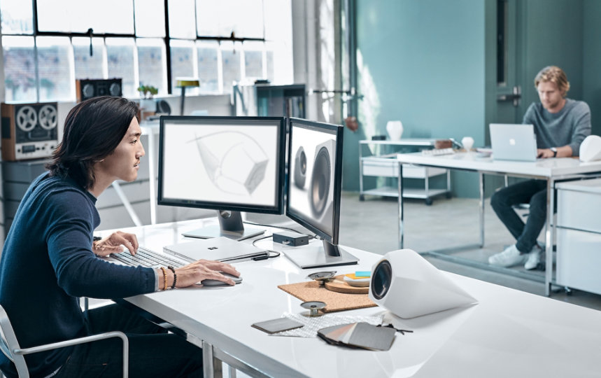  En man vid ett skrivbord använder en Surface Mouse och en Windows-enhet.