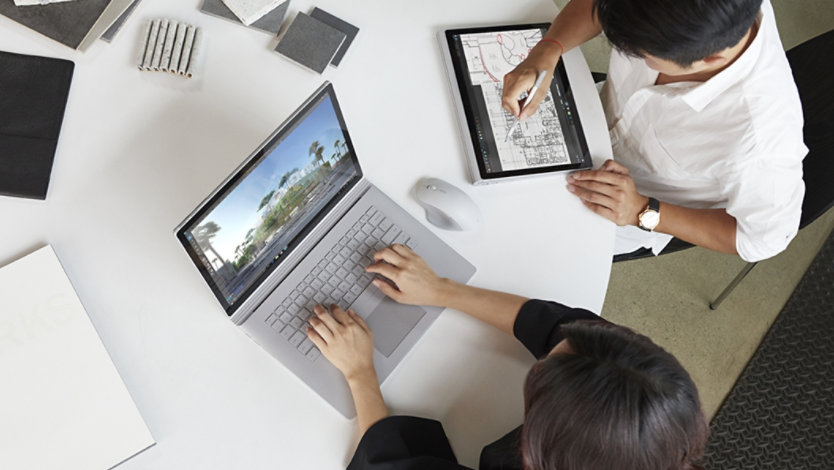 Two architects use a refurbished laptop and tablet for a design project.