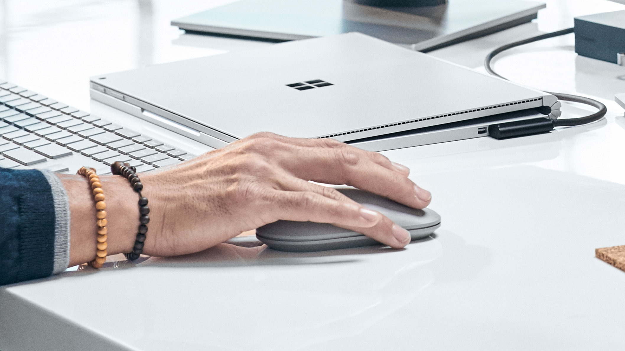 Ein Mann benutzt seine Surface Mouse mit einem Windows-Gerät an einem Schreibtisch.