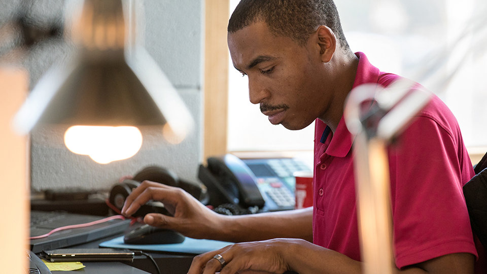 A person sits at a desk and reads a printout.
