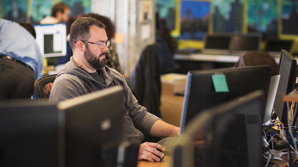 A person works on dual monitors in an office.