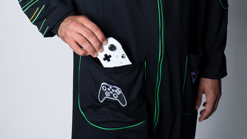 Person's hand placing Xbox controller in pocket of Xbox Series X Hooded Union Suit.