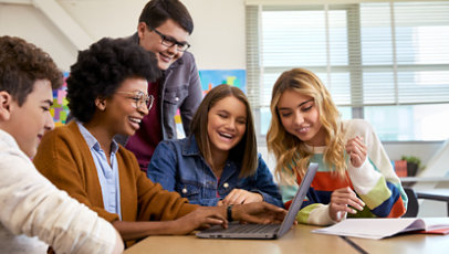 Cinco personas sonrientes miran juntas una computadora.