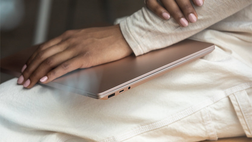 A person holds Surface Laptop 3 in their lap with U S B ports showing.