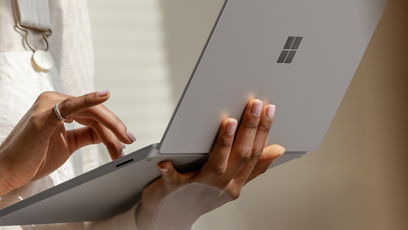 A person holds Surface Laptop 3 on their arm and using the touch pad