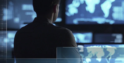 Una persona delante de una pared llena de pantallas que muestran mapas 