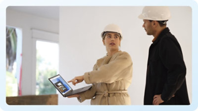 A man and woman standing in front of a laptop.