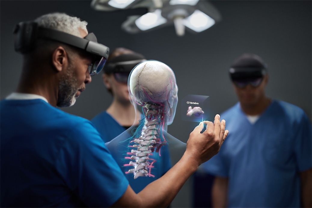 Three healthcare professionals wearing HoloLens 2 devices and looking at a mixed reality diagram of a human spine.
