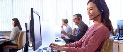 A woman wearing a headset and sitting at a desk.