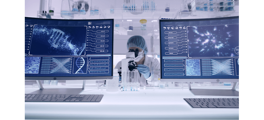 Uma pessoa olhando através de um microscópio em uma mesa com telas exibindo imagens de DNA e muito mais