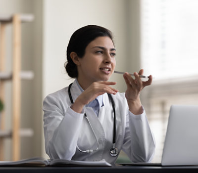 A woman in a white coat talking on a phone.