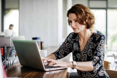 Pessoa usando um laptop em uma cafeteria, provavelmente aprendendo o que é um sistema de gerenciamento de ordens