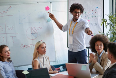 A couple of professional talking on a topic and one is presenting some data on board