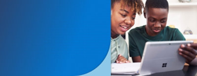 A person looking at a book and another looking at tablet