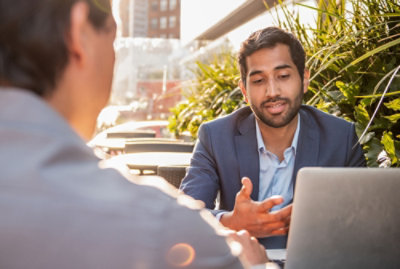 两名西装男士坐在现代办公室的桌子旁交谈。