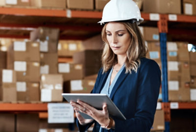 A person in a warehouse using a tablet, presumably using S C M to control the flow of goods and services