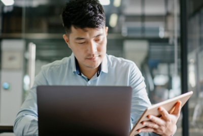 A person with a laptop also using a tablet