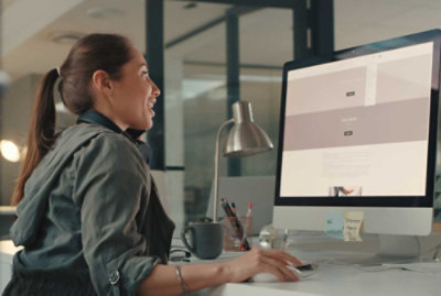 Osoba, která sedí u stolu a dívá se na počítač