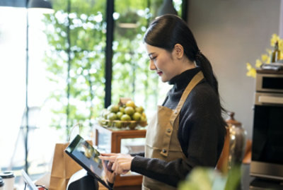 شخص واحد يقف ويفحص كمبيوترًا لوحيًا بوجه مبتسم