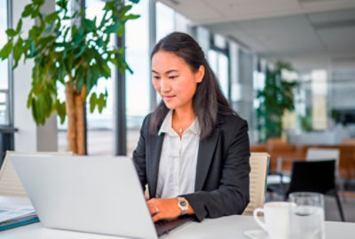 Usmívající se žena v černém saku pracující na přenosném počítači