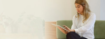 Eine Person, die auf einem Sofa sitzt und ein Tablet nutzt