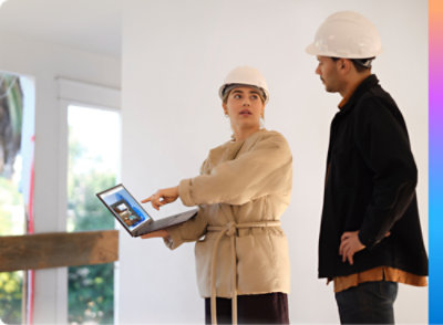 A woman and man in hardhats looking at a laptop.