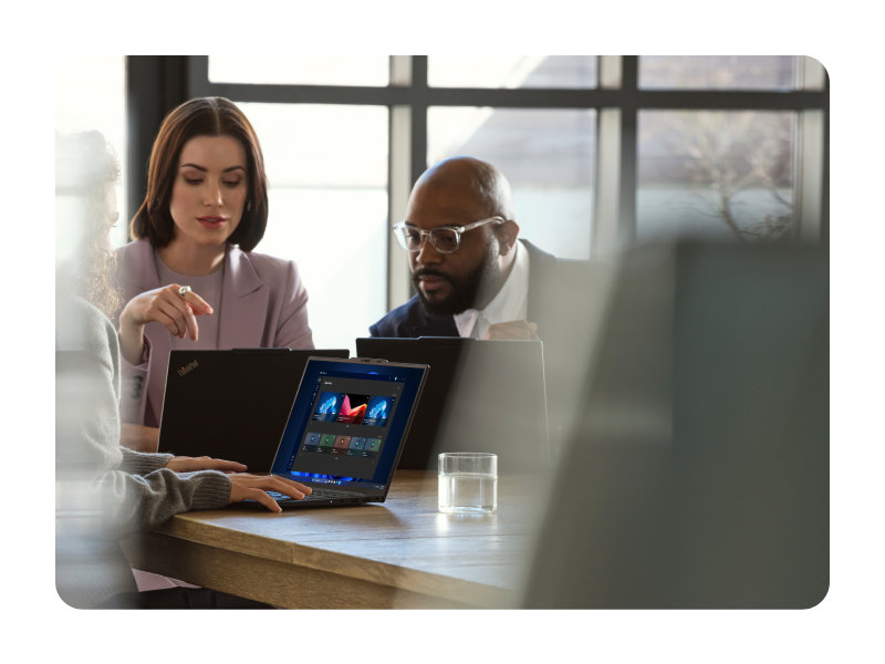People collaborating around a laptop in a modern workspace with one person guiding a discussion.