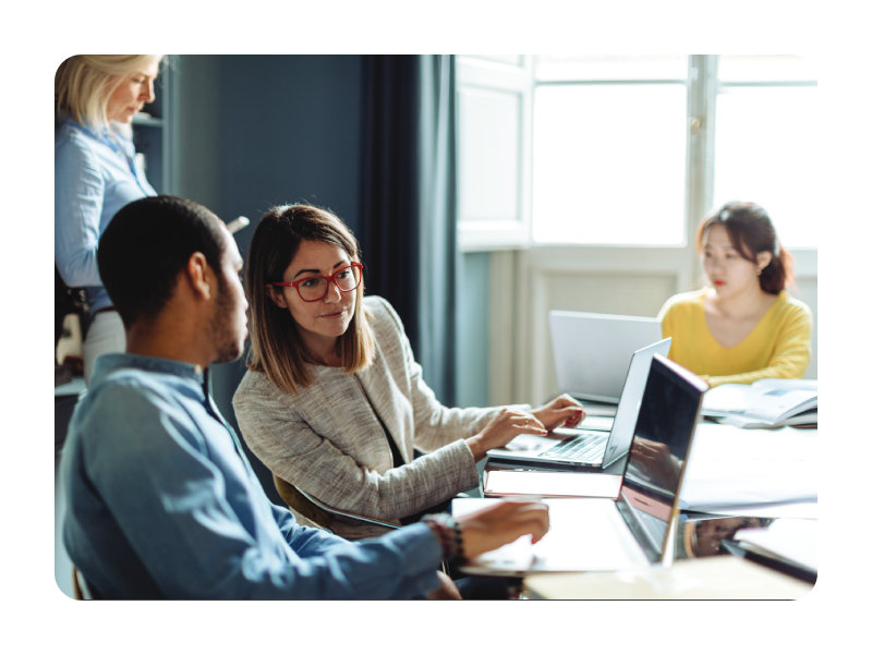 A small group of business professionals collaborating in a modern conference room, reviewing performance dashboards and charts