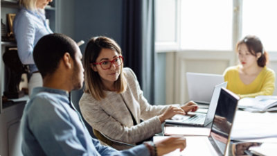 Two people working on laptop in office
