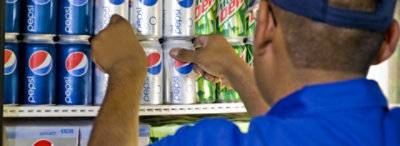 A Pepsi representative filling a refrigerator.