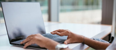 Person typing on a laptop in a room with natural light.