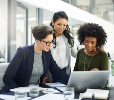 Three professionals collaborating over a laptop in a modern office setting.