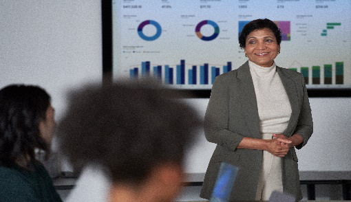 A professional woman delivers a presentation to an attentive audience.