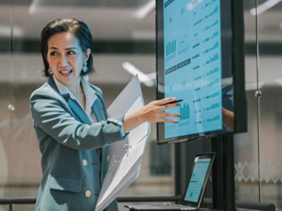 O femeie indicând spre un ecran