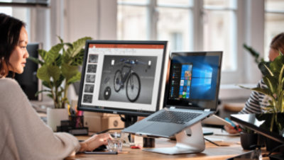 Una persona sentada ante su escritorio usa una portátil y un monitor de escritorio grande para trabajar en Visio.