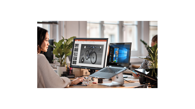 Eine Person, die an ihrem Schreibtisch mit einem Laptop und mit einem großen Desktopmonitor in Visio arbeitet.