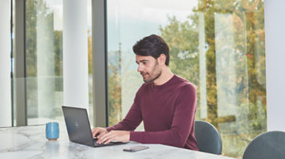 Person seated at a large table using a laptop
