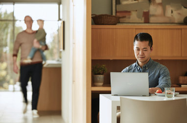 A man sitting at a table using a laptop.
