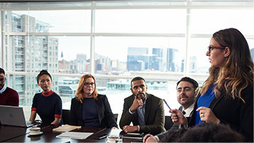 A person presenting to a group of people in a conference room