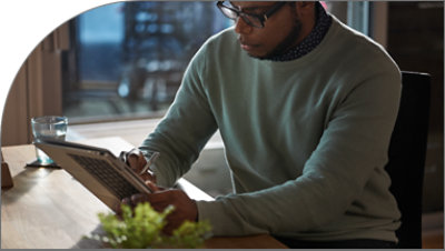 En person med glasögon som tittar ner på en surfplatta.