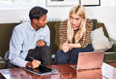 שני עמיתים היושבים על ספה ופותרים בעיות במכשירי Tablet