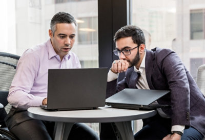 Two people working together at a small circular table, looking at a device