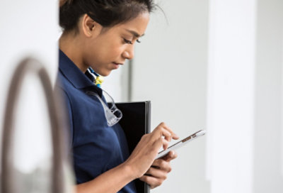 A person looking at a smartphone, with a keyboard for a tablet under their arm